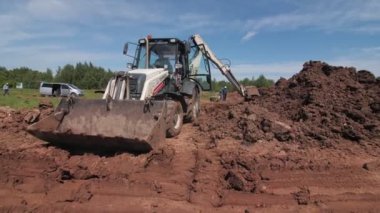 Büyük boş kovası olan kazıcı ve hendek yakınında işçiler.