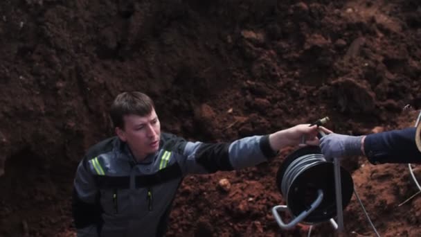 지진계를 사용하는 기술자가 깊은 도랑에 케이블을 박는다 — 비디오