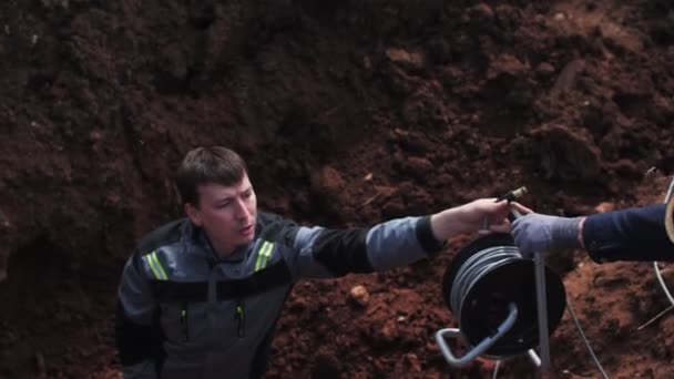 Engineer with seismological meter takes cable in deep trench — Stock Footage Engineer with seismological meter takes cable in deep trench Royalty Free Stock Video