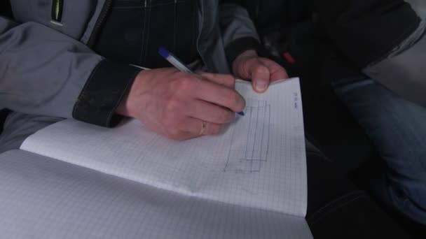 Anställda ritar enkelt schema av röret med hölje i anteckningsbok — Stockvideo