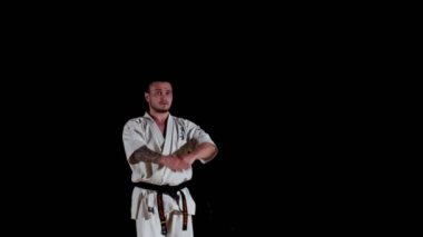 Beyazlı, siyah kuşaklı karate ustası spor salonunda egzersiz yapıyor.