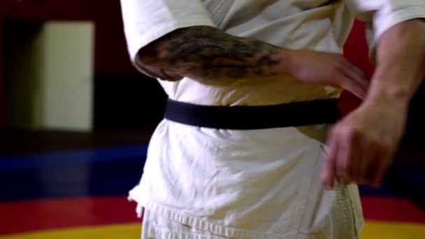 Мастер карате с татуировкой в кимоно галстуки черный пояс в тренажерном зале — стоковое видео