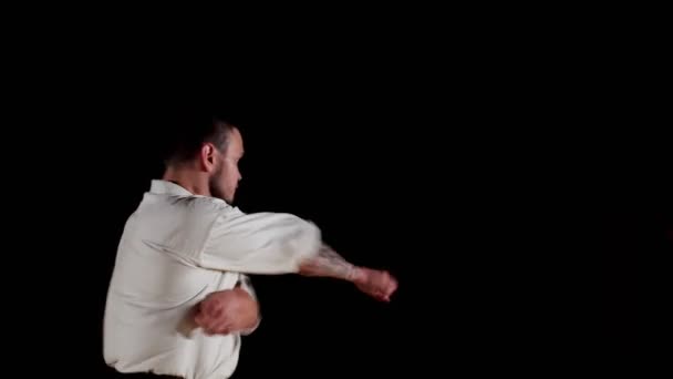 Karate harcos tetoválással a karján gyakorolja a sötét edzőteremben — Stock videók