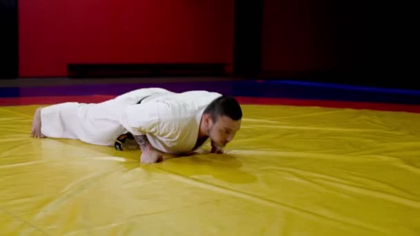 Karate vechter doet push-ups op vuisten op tatami bij de training — Stockvideo