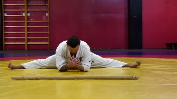 Sportovec v bílé uniformě dělá cvičení pro protahování — Stock video