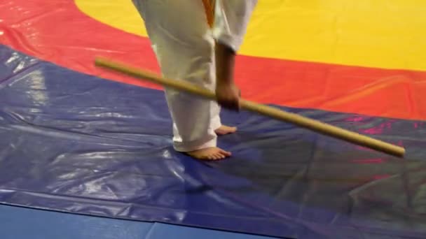 Hombre regordete en kimono toma y tuerce palo de madera en el gimnasio — Vídeos de Stock