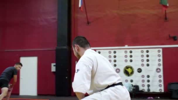 Entrenador de karate hace ataques dinámicos con los estudiantes en el gimnasio — Vídeo de stock