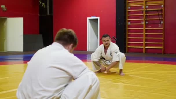 Maestro de karate hace ejercicio de estiramiento con estudiantes en el gimnasio — Vídeo de stock