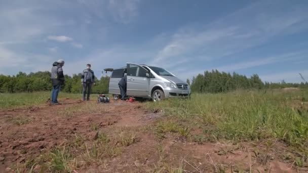 Trabajadores con máscaras con cable cerca de furgoneta gris en campo verde — Vídeo de stock