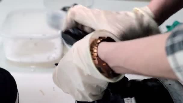 Рабочий моет обувь кисточкой и мылом за столом в магазине — стоковое видео