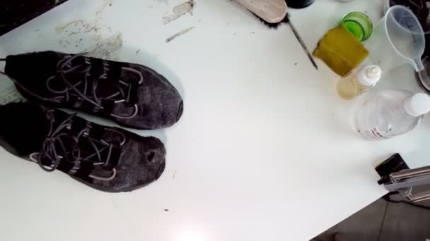 Man zet vernieuwde sneakers in de buurt van vuile vodden schoenen op tafel — Stockvideo