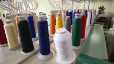 Rafta farklı renk iplikleri olan bobinlerin koleksiyonu