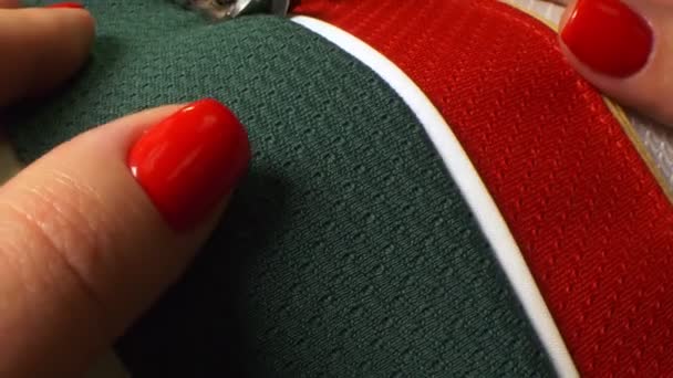 Mujer cose ropa con colores del equipo de hockey en taller — Vídeos de Stock
