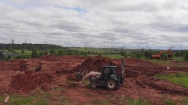 Kirli tepeyi aşan inşaat alanında beyaz kazıcı sürücüleri var.