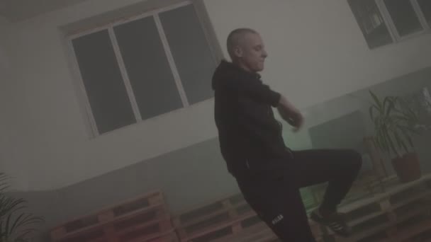 Man in zwart trainingspak danst tectonisch op houten pallets — Stockvideo