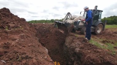 Kazıcı, sarı boruyla sipere toprak döker.