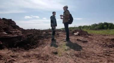 Genç adam siperin yanında duran meslektaşıyla konuşuyor.