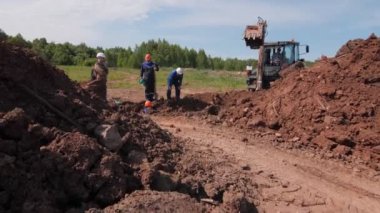 İşçiler ve liderler kazıcıyla siper kazmayı kontrol ediyorlar