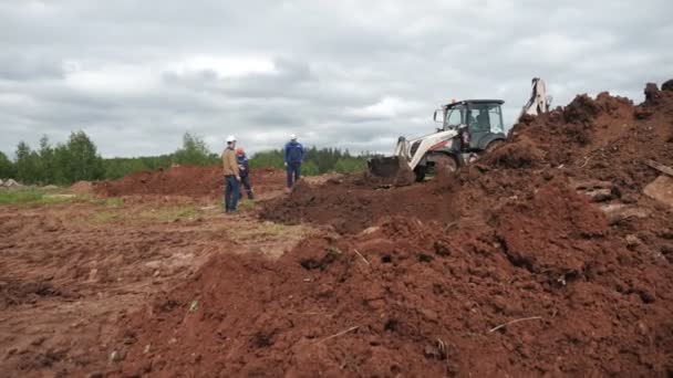 Dělníci se dívají na bagr stojící u zákopu na místě — Stock video