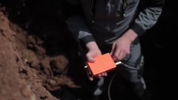 Employee connects cable to seismographical sensor in trench — Stock Footage Employee connects cable to seismographical sensor in trench Video Clip