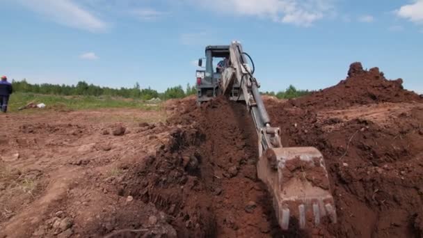 Worker controls digging of trench with excavator at site — Stock Video