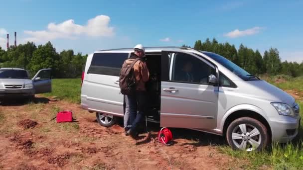 Meslektaşımla birlikte petrol sahasında gri minibüsün yanında duruyoruz. — Stok video