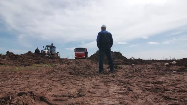 Travailleur en uniforme marche au camion benne sur grand champ pétrolifère — Video