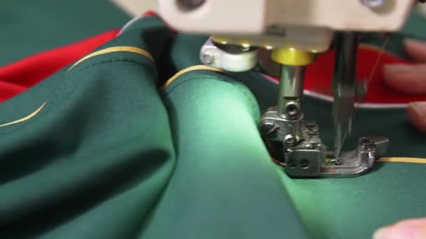 Sömmerska syr hockey uniform av grönt tyg med hjälp av maskin — Stockvideo