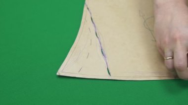 Terzi, dikiş desenli yeşil kumaşın detaylarını çizer