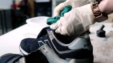 İşçiler spor ayakkabısının dilini dükkandaki bezle silerler.