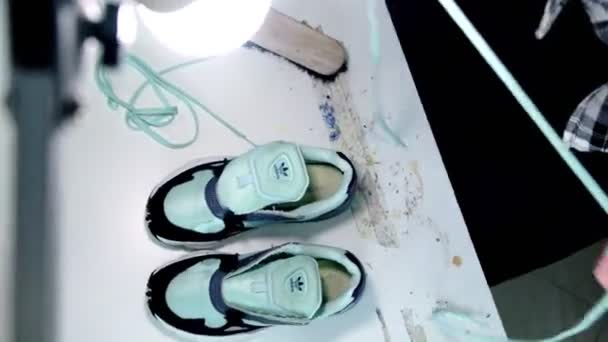 Zapatillas de deporte renovadas verdes de los cordones del trabajador en primer plano de la mesa blanca — Vídeo de stock