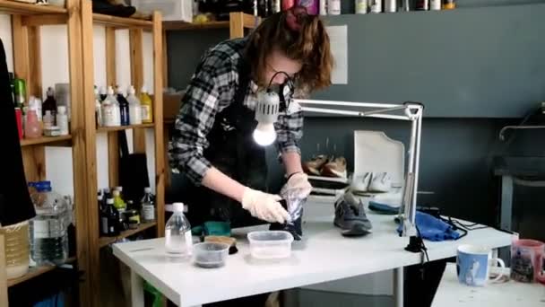 Работник моет язык кроссовок щеткой и мылом за столом — стоковое видео