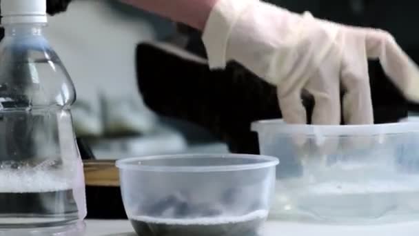 Человек кладет кисть в моющее средство, чтобы мыть кроссовки за столом — стоковое видео