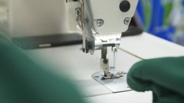 İşçi dikiş makinesinin yanında yeşil kumaş örtüsü alıyor