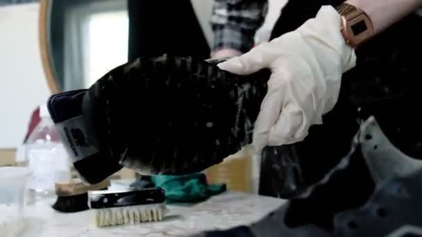 Женщина моет кроссовки щеткой и тряпкой за столом в магазине — стоковое видео