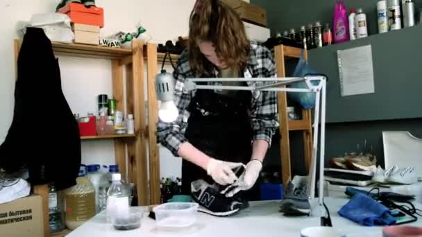 Женщина моет язык кроссовок в мастерской по ремонту обуви — стоковое видео