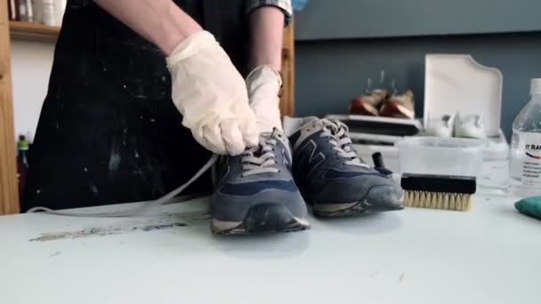 Trabajador con camisa a cuadros se quita los cordones de las zapatillas viejas — Vídeos de Stock