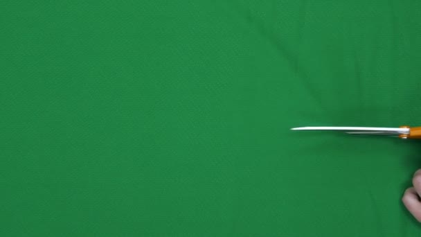 裁缝师在桌旁用剪刀剪下鲜艳的绿色面料 — 图库视频影像
