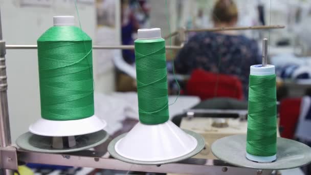 Катушки зеленого цвета с резьбой на стойке в швейной мастерской — стоковое видео