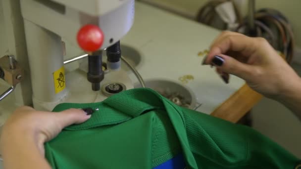 Un employé installe des oeillets dorés dans un uniforme de hockey vert — Video