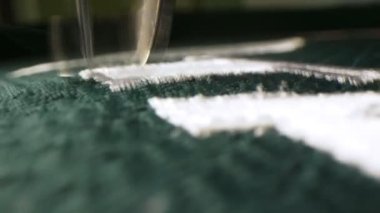 Makine aracı yeşil hokey üniformasına beyaz harf dikiyor