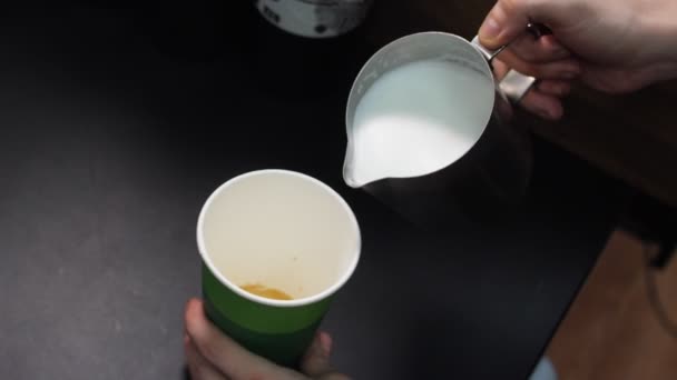 Barista añade leche al sabroso café en taza de papel en la mesa — Vídeos de Stock