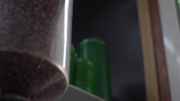 Movimiento pasado contenedor de vidrio de la máquina con granos de café — Vídeos de Stock