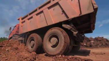 Bahşiş kamyonu kazıcının yanından geçerek toprak yığınının yanında duruyor.