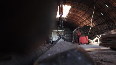 Atölyenin kirli zemininde metal dillerle tutulan eski kütükler.