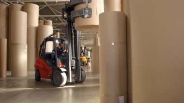 Forklift yükleyicisi depoda büyük miktarda kağıt taşıyor.