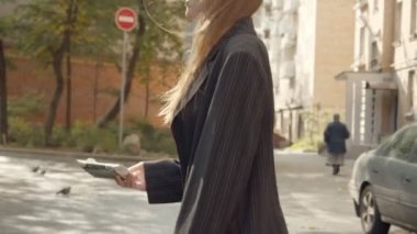 Sarışın kadın içkiyi sokaktaki çöp kutusuna taşır.