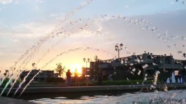 Şehir parkında akşam vakti aydınlanan fıskiyelerin taze fıskiyeleri.