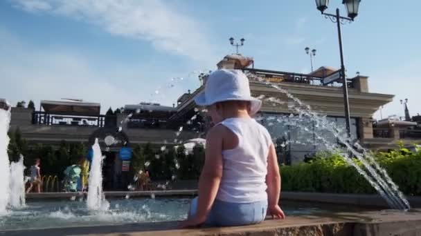 Маленька дитина в Панамі сидить на парапеті біля фонтану в парку — стокове відео
