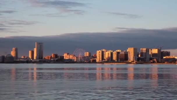 Stad met hoge gebouwen en reuzenrad aan rivieroever — Stockvideo